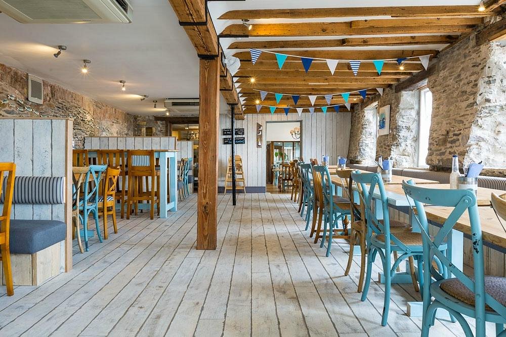 Sharksfin Mevagissey — a bright coastal dining room with bunting and pale timber.